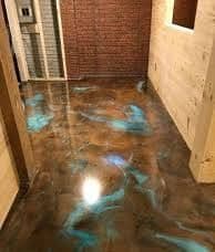 Decorative epoxy floor with a glossy brown finish and blue marbled patterns in a modern space.