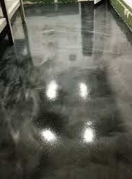 Polished black epoxy floor reflecting overhead lights in a modern interior space.