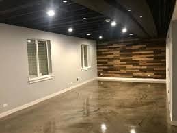 Modern empty room with polished concrete floor, wooden accent wall, and bright recessed lighting.