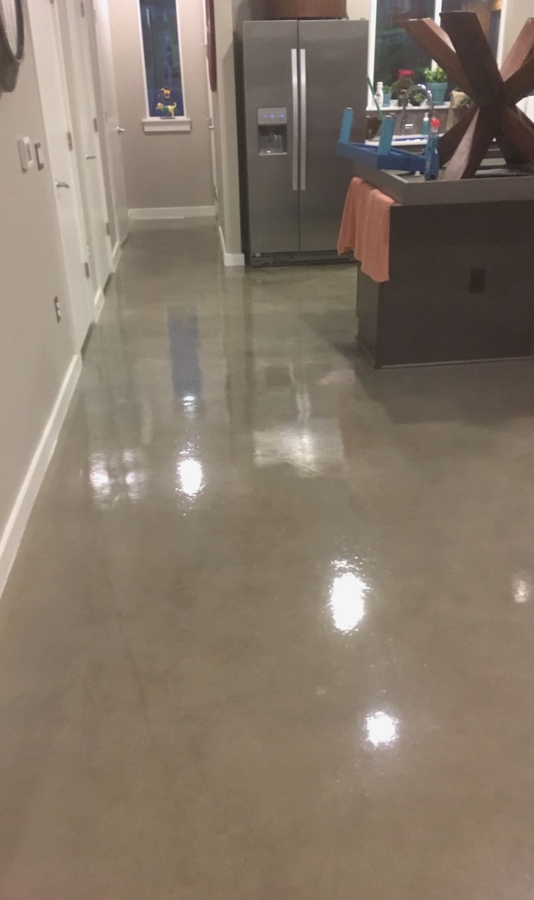 Polished concrete flooring in a modern kitchen with stainless steel refrigerator and wooden decor.
