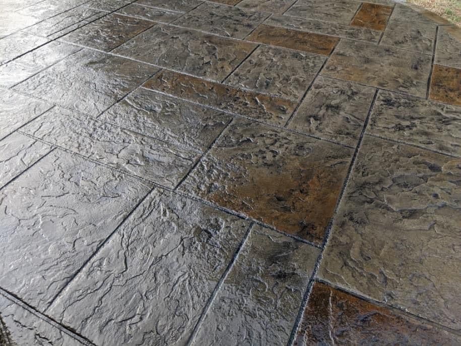 Textured slate-patterned concrete patio with a dark color scheme and weathered finish.