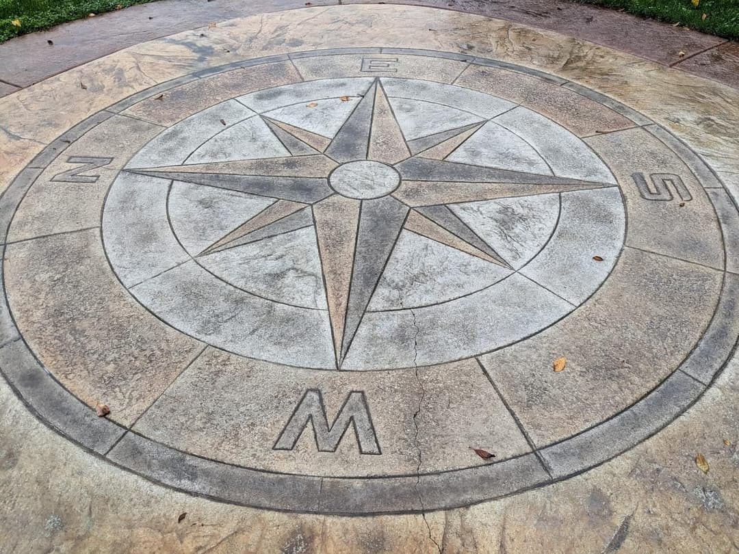 Compass rose embedded in stone, featuring cardinal directions N, E, S, W.