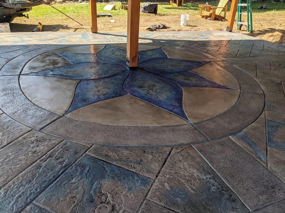 Decorative stamped concrete patio with a floral design in blue and gray tones.