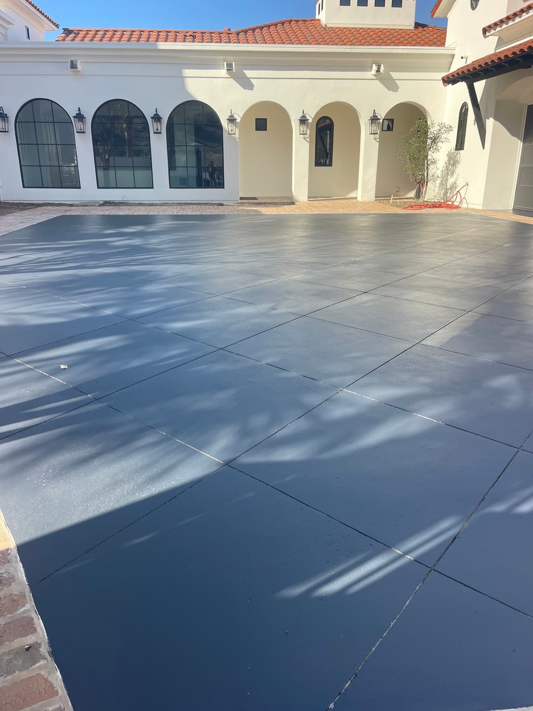 Freshly painted blue concrete patio with arched windows and Mediterranean-style architecture.