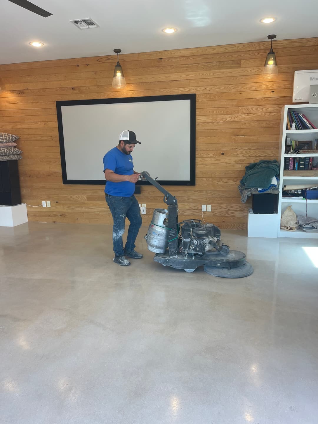 Man polishing a concrete floor with a machine in a modern interior space.
