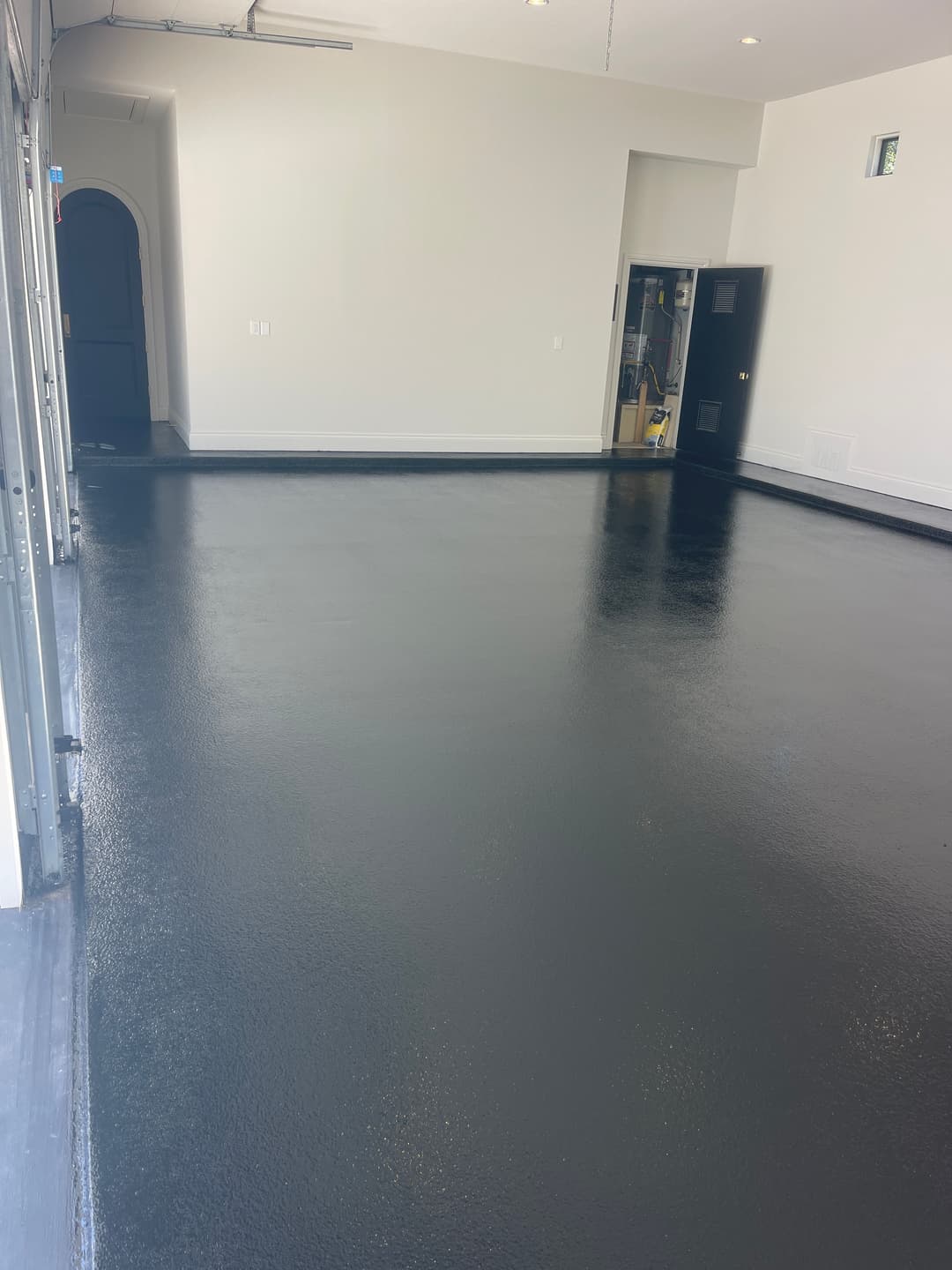 Sleek black epoxy garage floor with ample natural light and open space.