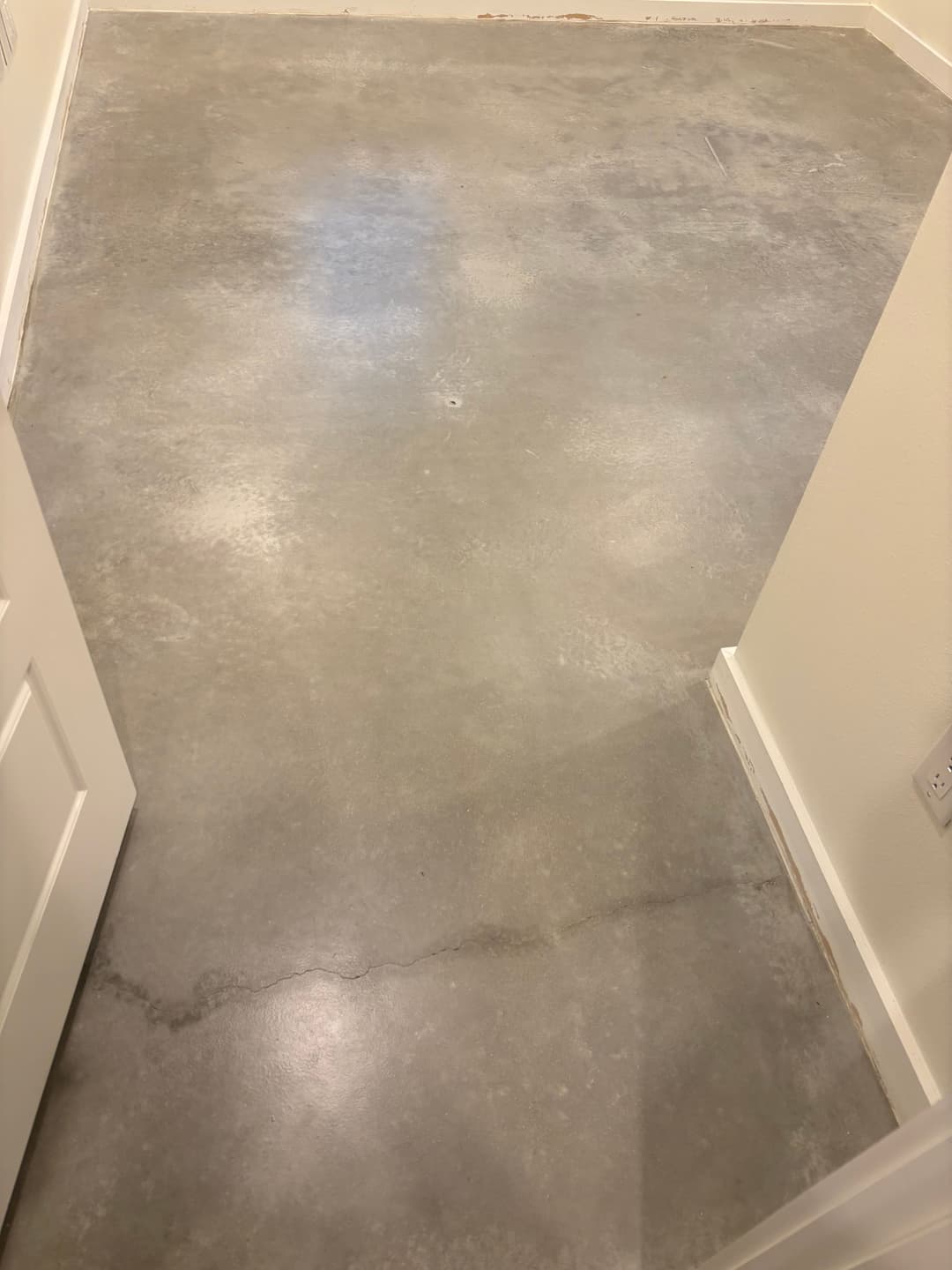 Interior view of a polished concrete floor in a modern room with white walls.