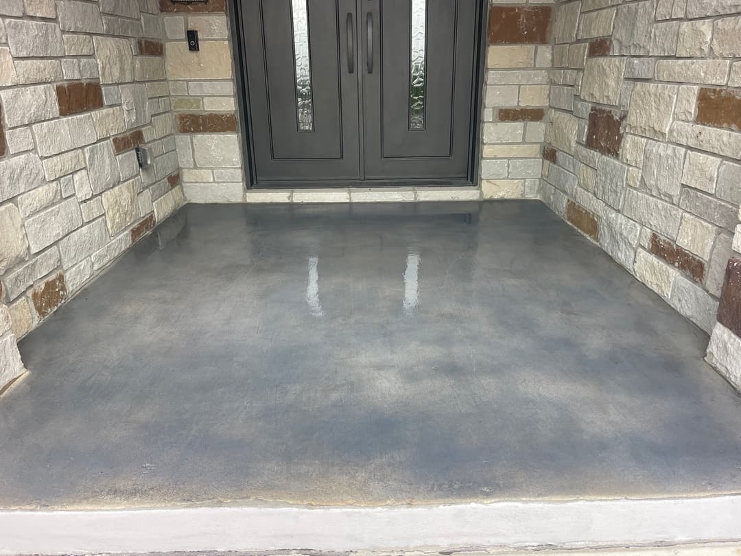 Polished concrete porch with stone accents leading to modern double doors.