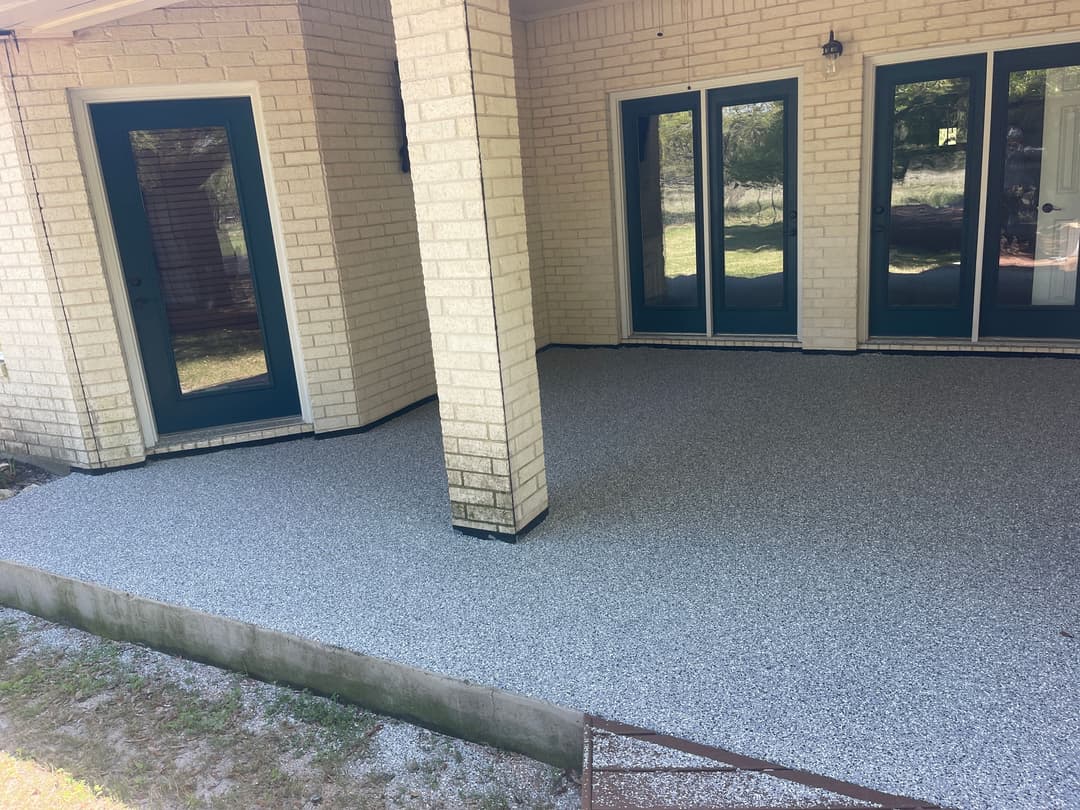 Newly renovated outdoor patio with gray epoxy flooring and brick columns. Bright, clean design.