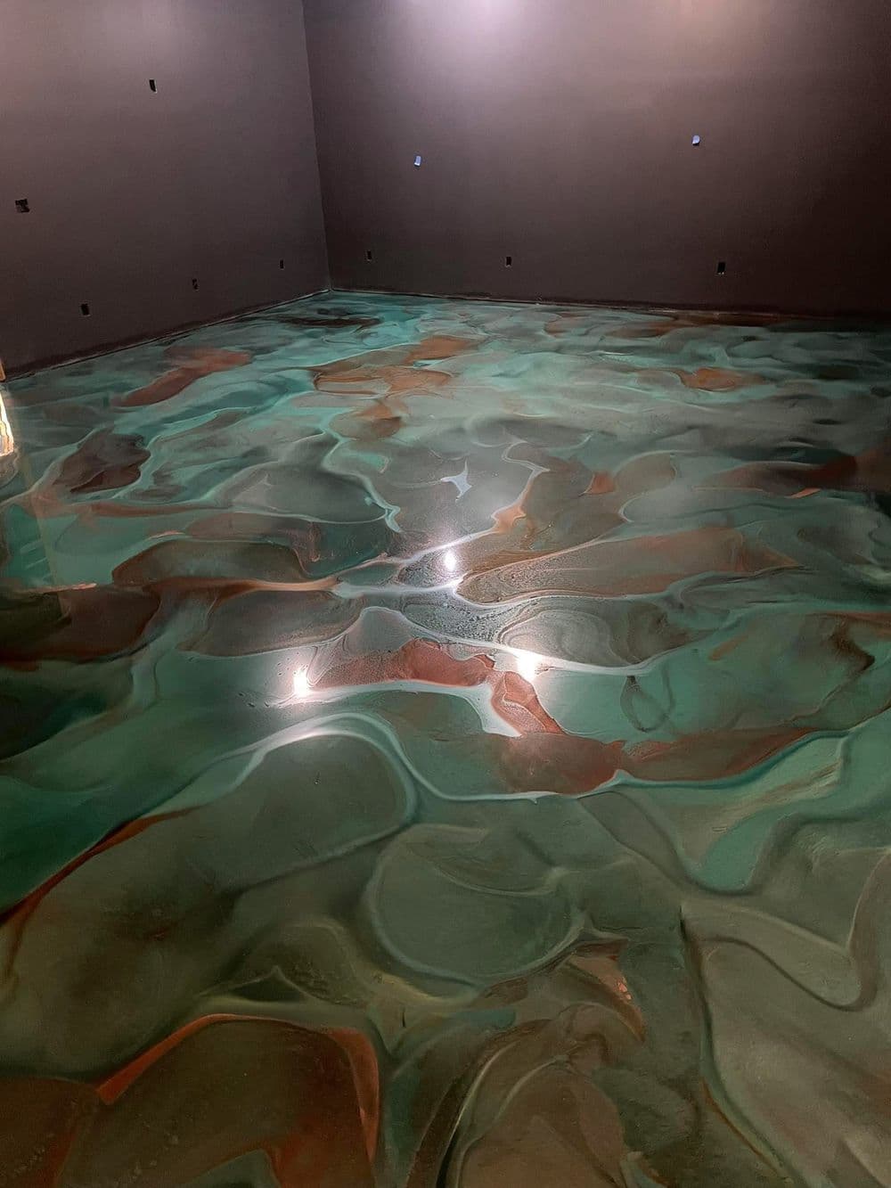 Epoxy resin floor with swirls of teal and copper in a modern interior setting.